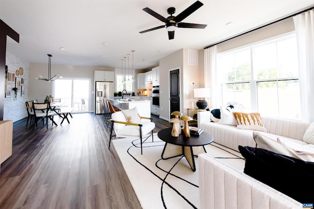 living room with a wealth of natural light, sink, ceiling fan, and dark hardwood / wood-style floors