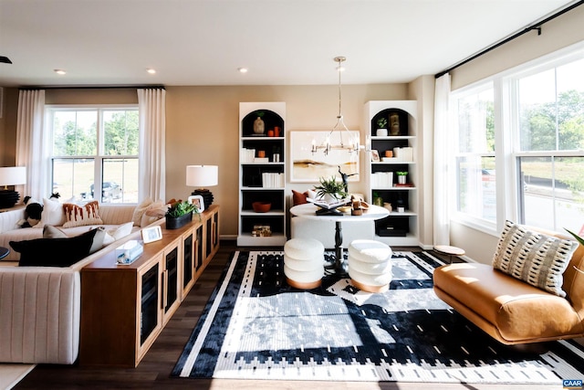 sitting room featuring built in shelves, dark hardwood / wood-style flooring, and an inviting chandelier