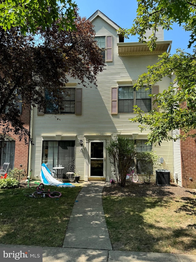 view of property featuring central air condition unit and a front lawn