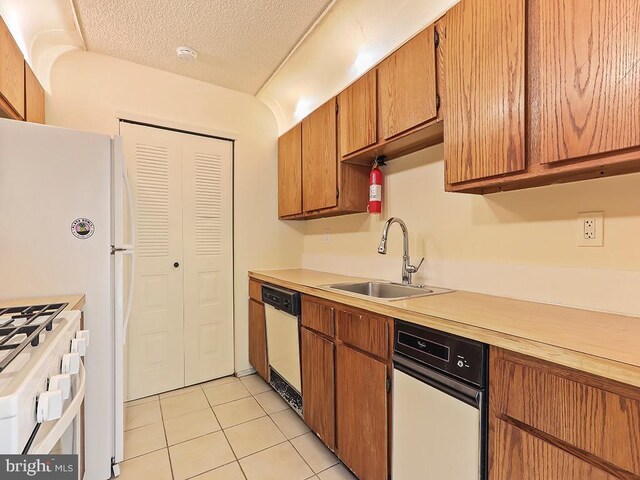 kitchen featuring white dishwasher, sink, a textured ceiling, range with gas stovetop, and light tile patterned flooring