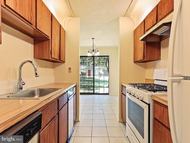 kitchen with sink, custom exhaust hood, white appliances, a chandelier, and a textured ceiling