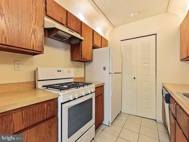 kitchen with a textured ceiling, white appliances, and light tile patterned floors