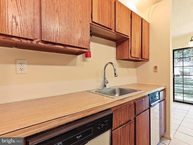 kitchen featuring light tile patterned flooring, sink, dishwashing machine, and dishwasher