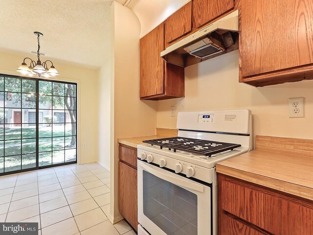 kitchen featuring white range with gas cooktop, hanging light fixtures, custom exhaust hood, a textured ceiling, and an inviting chandelier