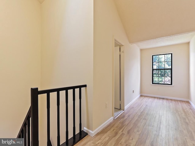 hallway with light hardwood / wood-style flooring and lofted ceiling