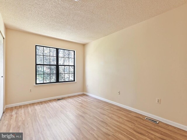 unfurnished room with a textured ceiling and light hardwood / wood-style floors