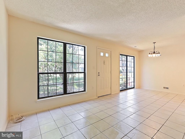 entryway with a wealth of natural light, an inviting chandelier, and light tile patterned floors