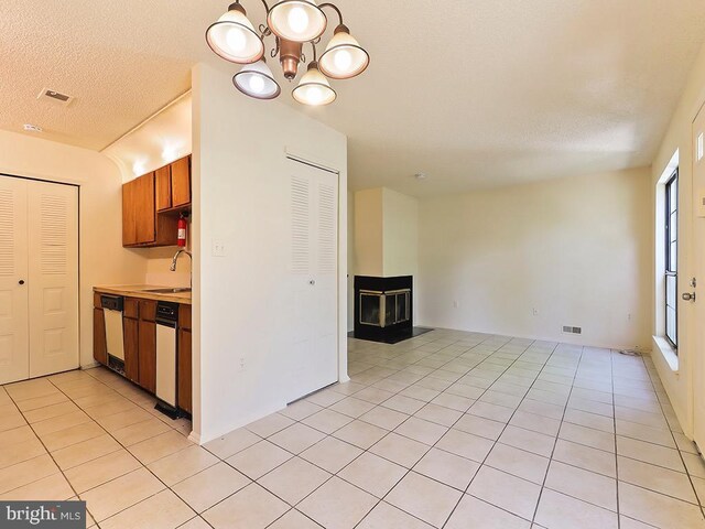 kitchen featuring dishwasher, white dishwasher, light tile patterned floors, sink, and an inviting chandelier