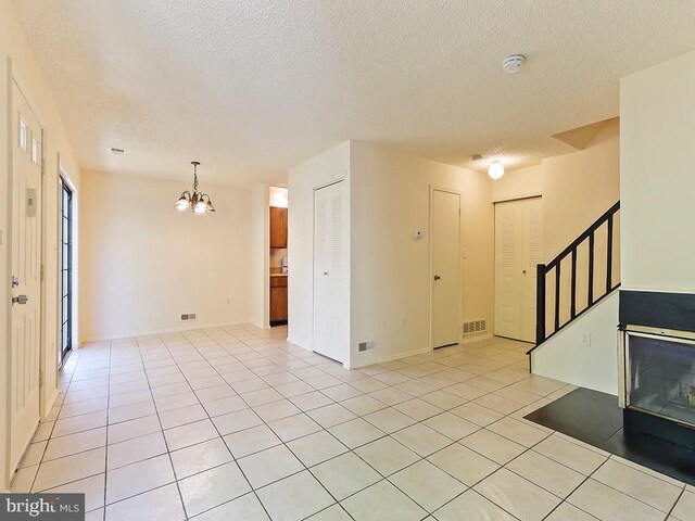 tiled foyer featuring an inviting chandelier and a textured ceiling