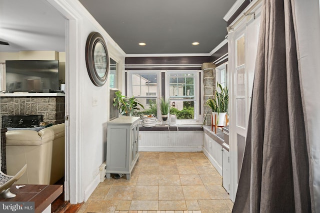 interior space with ornamental molding, stacked washing maching and dryer, and a stone fireplace