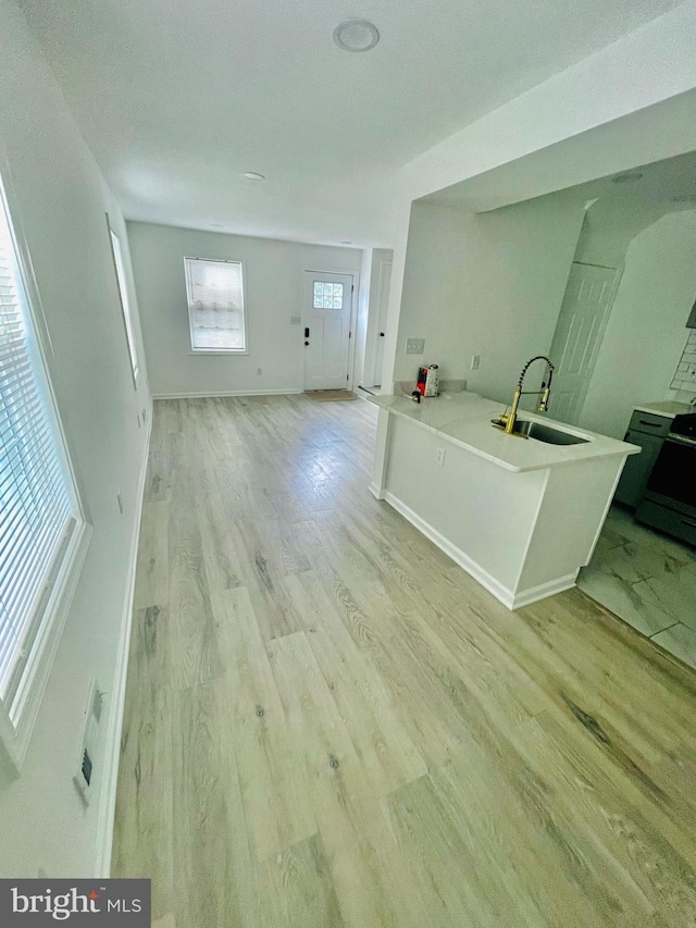 interior space featuring sink, kitchen peninsula, and light wood-type flooring