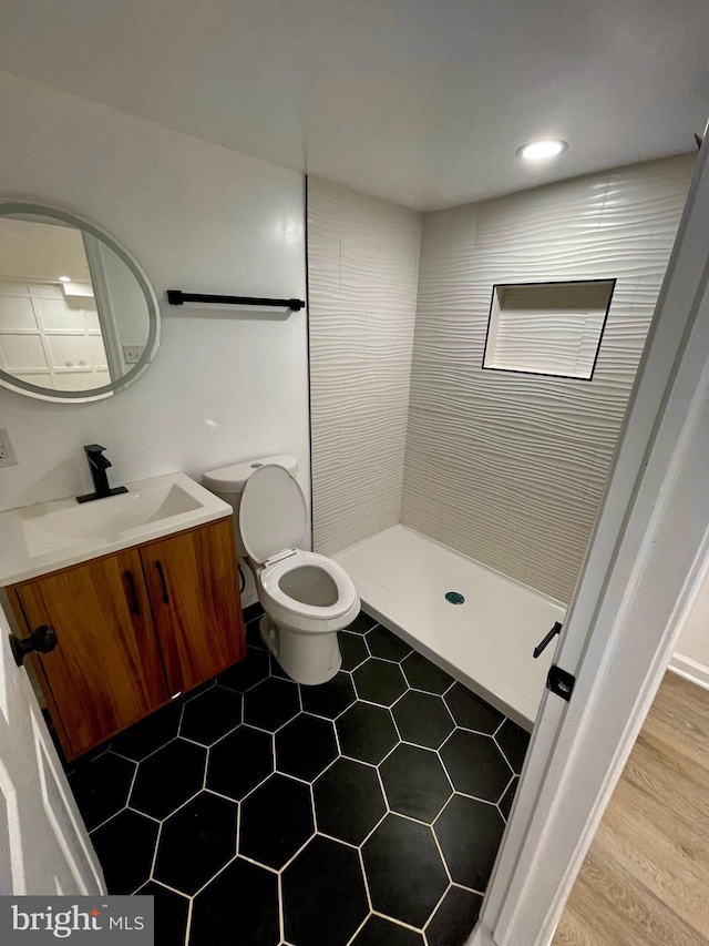 bathroom featuring vanity, tiled shower, toilet, and hardwood / wood-style flooring