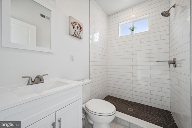 bathroom featuring toilet, vanity, and a tile shower