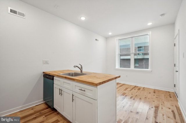 kitchen with dishwasher, light hardwood / wood-style floors, sink, white cabinets, and butcher block counters