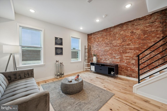 living room with light hardwood / wood-style floors and brick wall