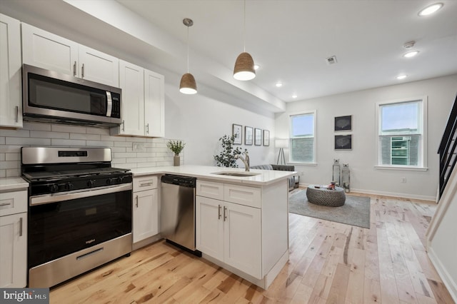 kitchen with white cabinetry, stainless steel appliances, pendant lighting, and kitchen peninsula