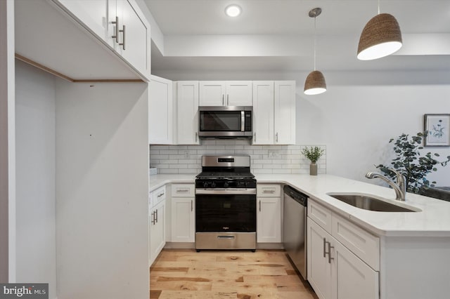 kitchen featuring white cabinets, appliances with stainless steel finishes, decorative light fixtures, sink, and kitchen peninsula