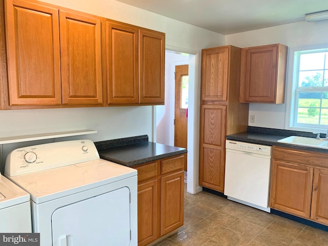 kitchen with independent washer and dryer, white dishwasher, and sink