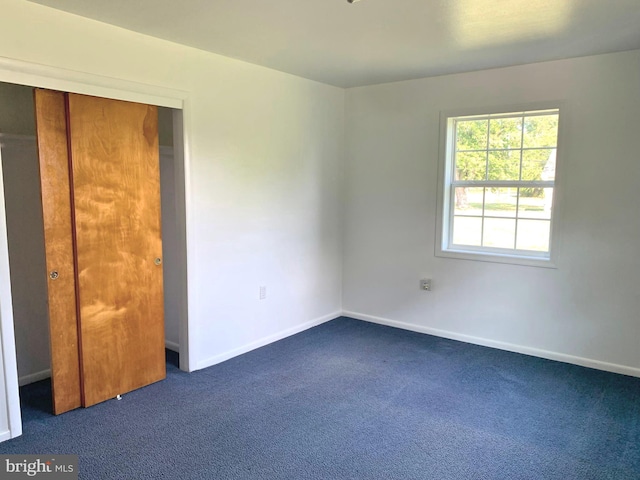 unfurnished bedroom with a closet and dark colored carpet