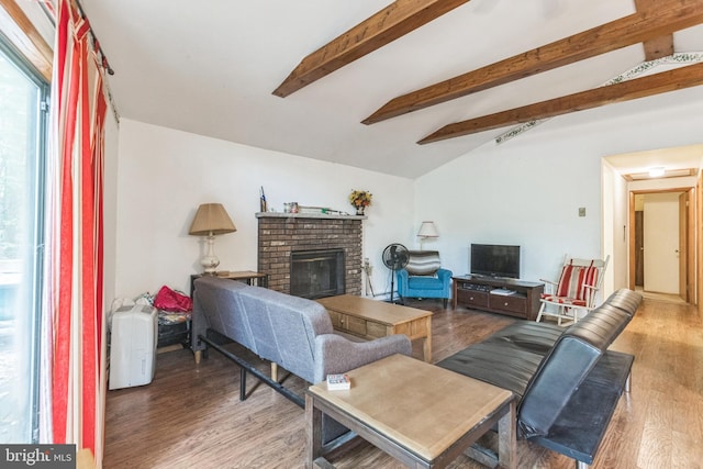 living room with hardwood / wood-style floors, lofted ceiling with beams, and a brick fireplace