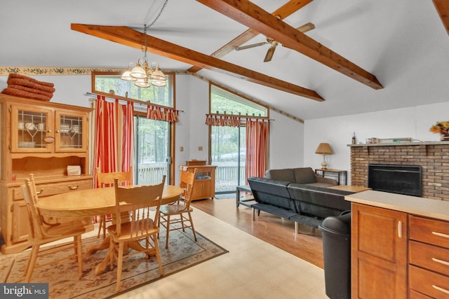 dining area with ceiling fan with notable chandelier, beam ceiling, high vaulted ceiling, a fireplace, and light hardwood / wood-style floors