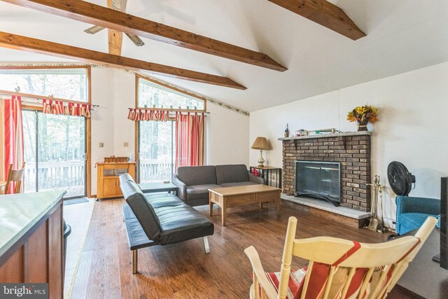 living room with beam ceiling, hardwood / wood-style flooring, a brick fireplace, and plenty of natural light