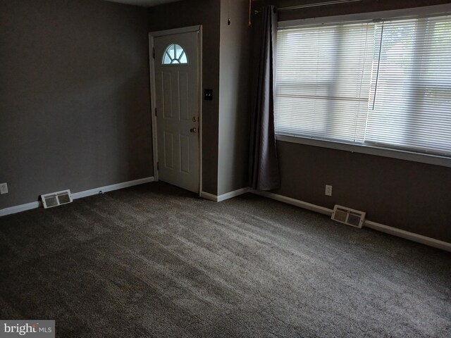 foyer entrance featuring dark colored carpet