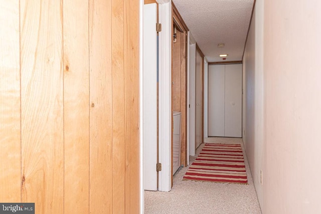 hallway featuring light colored carpet and a textured ceiling