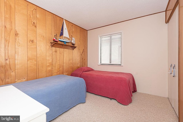 bedroom with wood walls, light colored carpet, and a textured ceiling