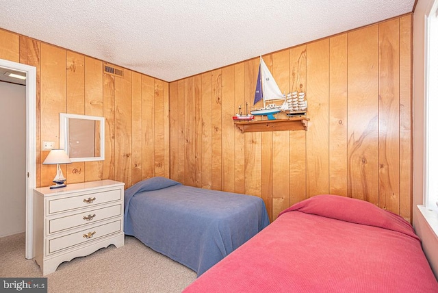 carpeted bedroom featuring wood walls and a textured ceiling