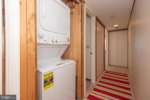 washroom with stacked washer / drying machine and a textured ceiling