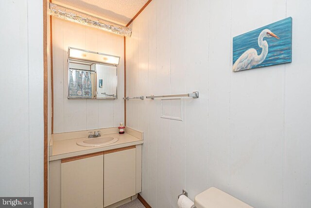 bathroom with vanity, toilet, and wooden walls