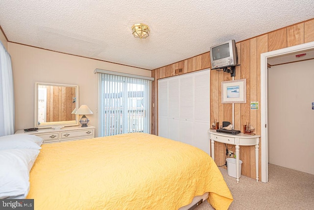 bedroom featuring wooden walls, a closet, light carpet, and a textured ceiling