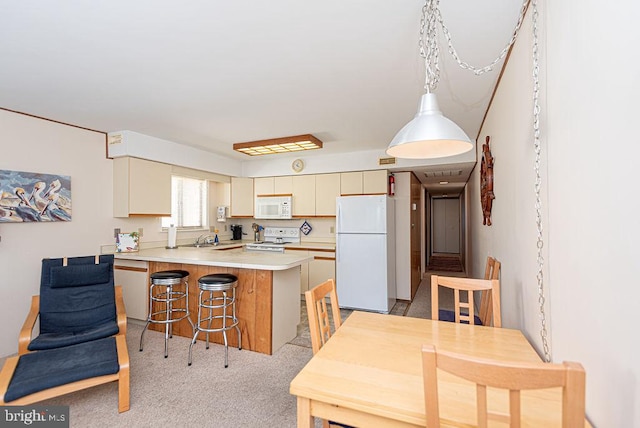 kitchen featuring kitchen peninsula, light carpet, white appliances, sink, and cream cabinets