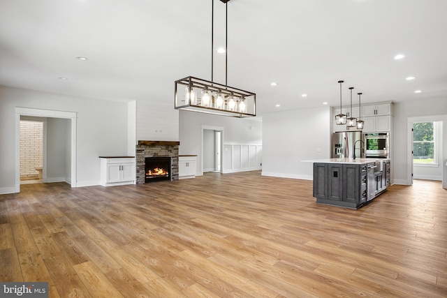 unfurnished living room featuring a stone fireplace and light hardwood / wood-style floors