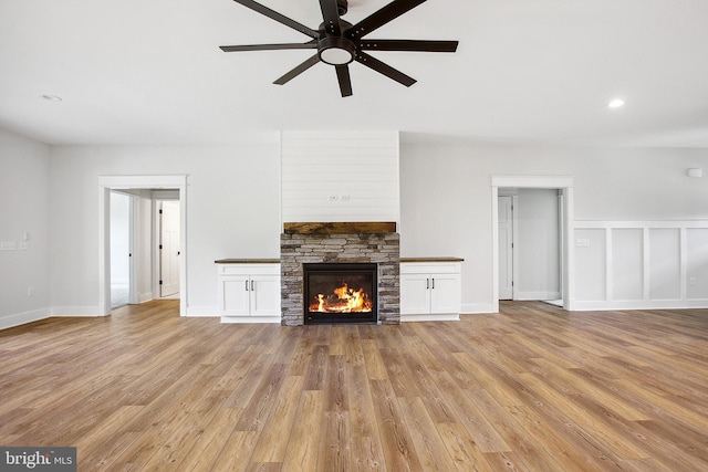 unfurnished living room with ceiling fan, light wood-type flooring, and a fireplace