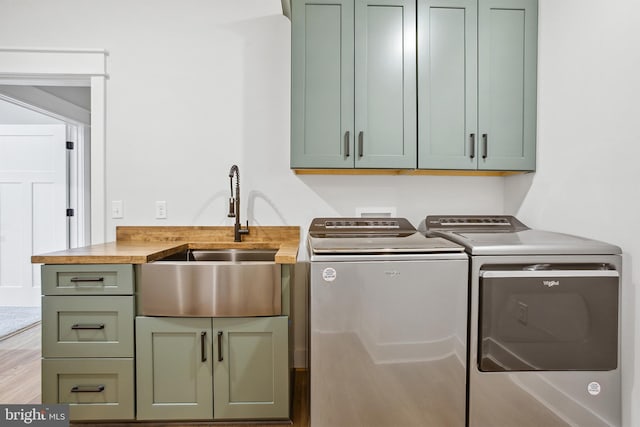 clothes washing area featuring cabinets, sink, and washing machine and clothes dryer