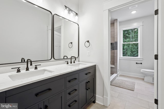 bathroom with toilet, vanity, tiled shower, and tile patterned floors