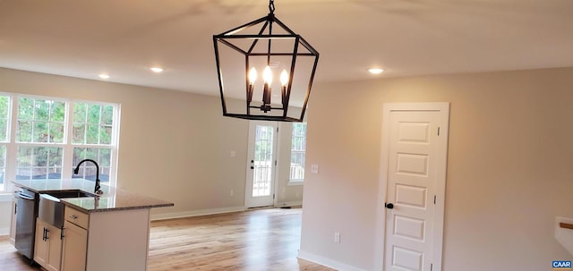 kitchen featuring stone counters, white cabinetry, hanging light fixtures, stainless steel dishwasher, and light hardwood / wood-style floors