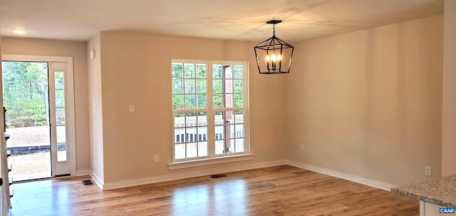 unfurnished dining area with an inviting chandelier and light hardwood / wood-style floors