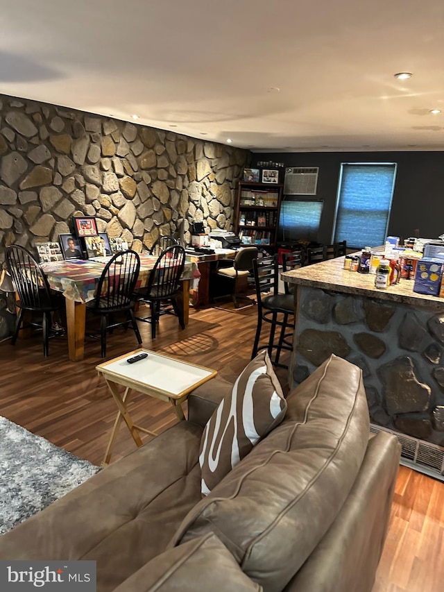 living room featuring wood-type flooring and a wall unit AC