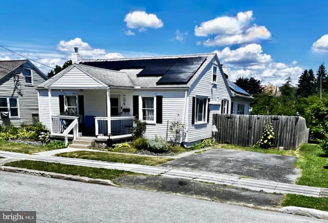 bungalow featuring solar panels and a porch