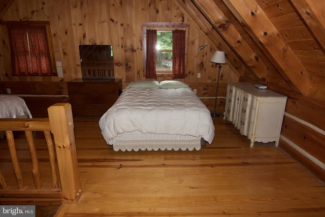 bedroom featuring wood walls, hardwood / wood-style flooring, and lofted ceiling with beams