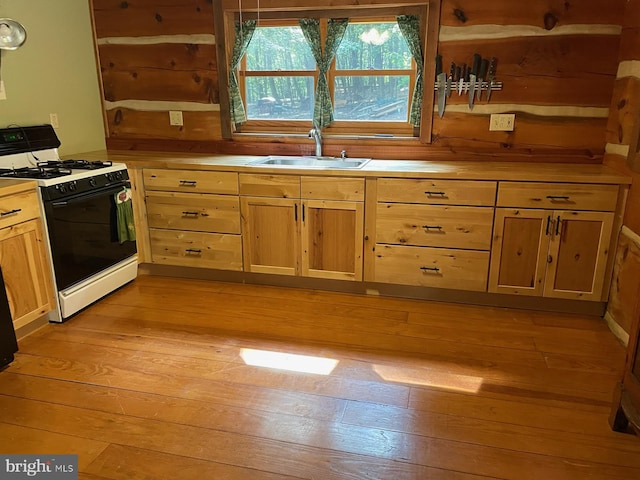 kitchen with light hardwood / wood-style flooring, white range with gas stovetop, and sink