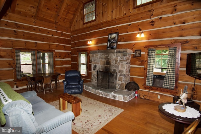 living room with wood-type flooring, plenty of natural light, wood walls, and a stone fireplace