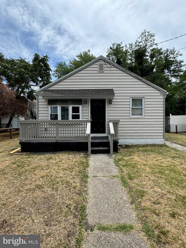 bungalow-style house with a wooden deck and a front lawn