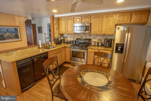 kitchen with tasteful backsplash, kitchen peninsula, sink, stainless steel appliances, and light stone counters