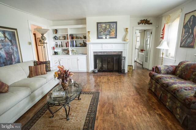 living room featuring built in shelves, a fireplace, and dark hardwood / wood-style flooring