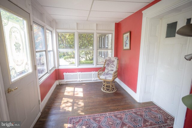 sunroom with radiator, a paneled ceiling, and plenty of natural light