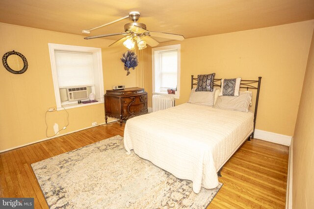 bedroom featuring ceiling fan, radiator, cooling unit, and hardwood / wood-style flooring